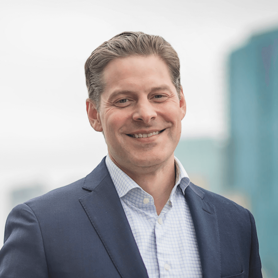 A portrait of Dr. Johnson smiling while wearing a navy blue suit in front of the Ft. Worth skyline